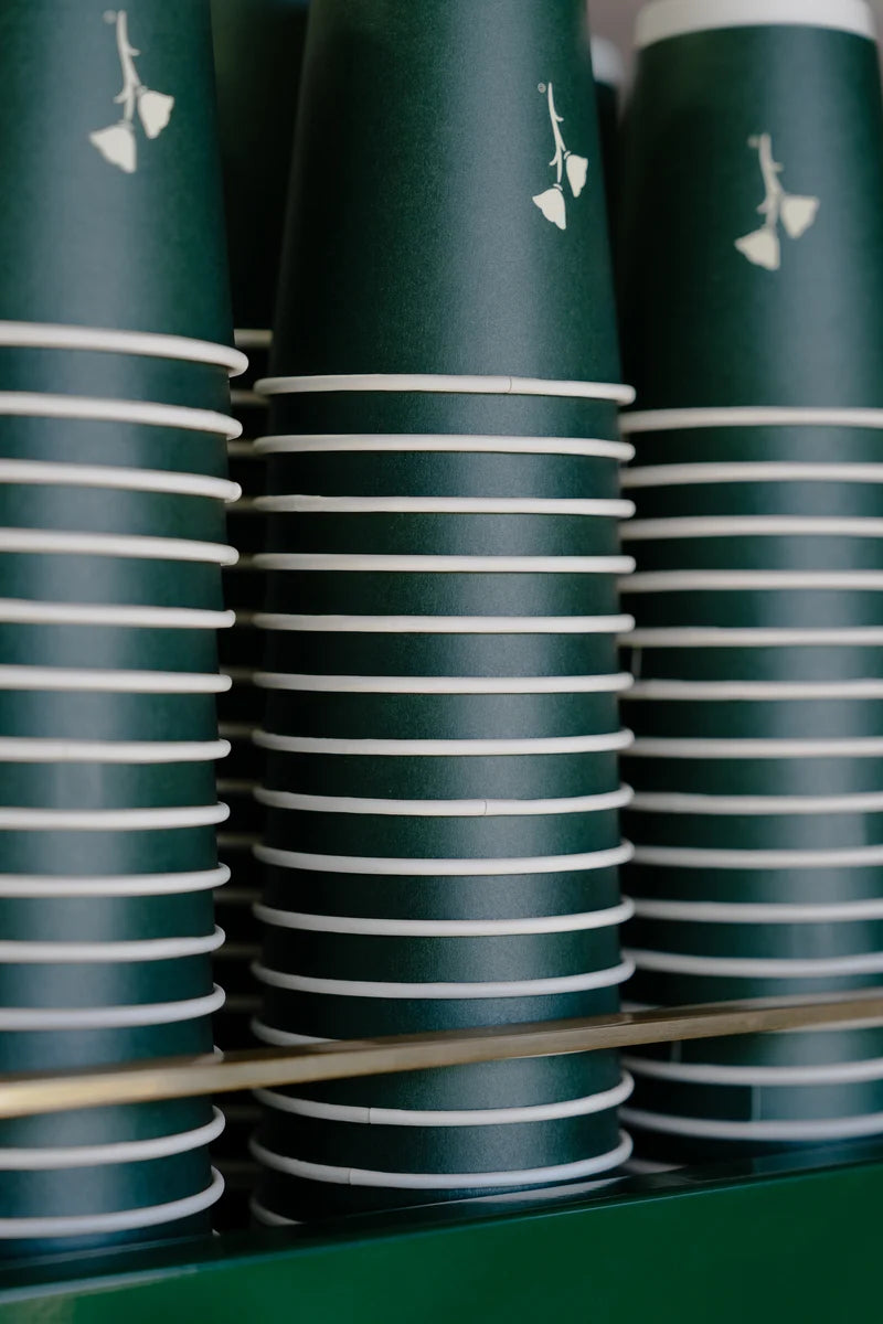 The dark green Pad One paper cup with cream print