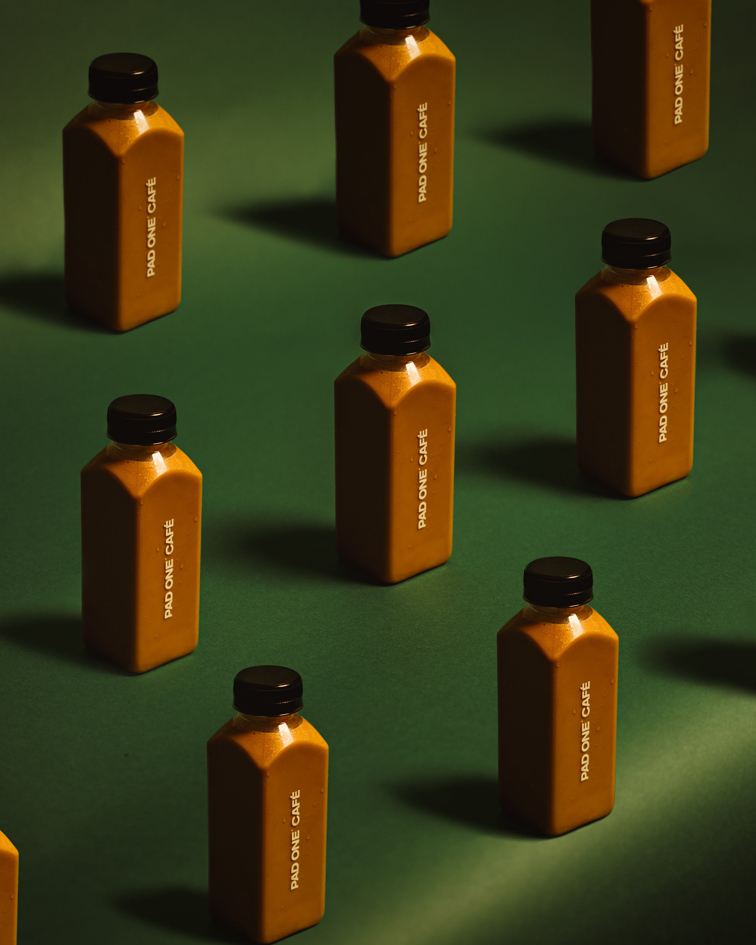 Pad One Café bottled coffee arranged on a green background